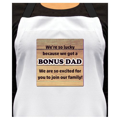 Personalized apron personalized with natural wood pattern and the sayings "We're so lucky because we got a We are so excited for you to join our family!" and "BONUS DAD"