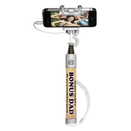 Personalized selfie stick personalized with natural wood pattern and the sayings "We're so lucky because we got a We are so excited for you to join our family!" and "BONUS DAD"
