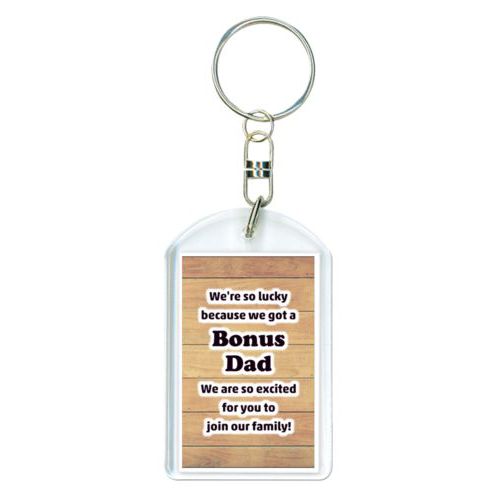 Personalized plastic keychain personalized with natural wood pattern and the saying "We're so lucky because we got a Bonus Dad We are so excited for you to join our family!"