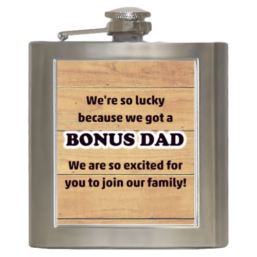 Personalized 6oz flask personalized with natural wood pattern and the sayings "We're so lucky because we got a We are so excited for you to join our family!" and "BONUS DAD"